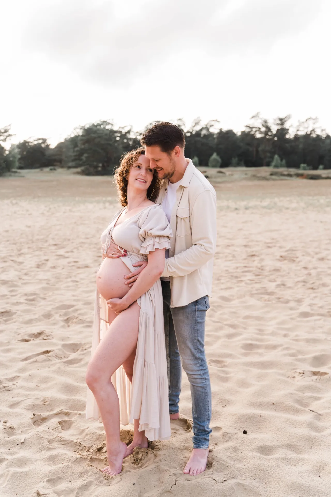 Stel in de duinen tijdens een zwangerschapsshoot